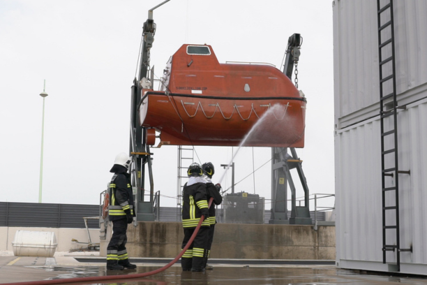 Un grupo de bomberos realiza un rescate en altura en un edificio elevado, utilizando arneses, cuerdas y equipo especializado. La escena muestra a los rescatistas trabajando con precisión y coordinación en un entorno de alto riesgo, mientras uno de ellos asegura cuidadosamente a una persona en una camilla suspendida. De fondo, se aprecia un paisaje urbano y una estructura industrial, destacando el contexto de emergencia en el que se encuentran.






